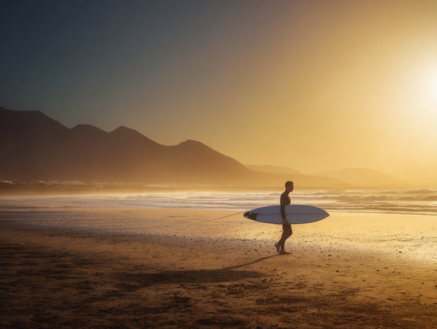 Surfer, der eine Welle an einem Strand in Lanzarote reitet